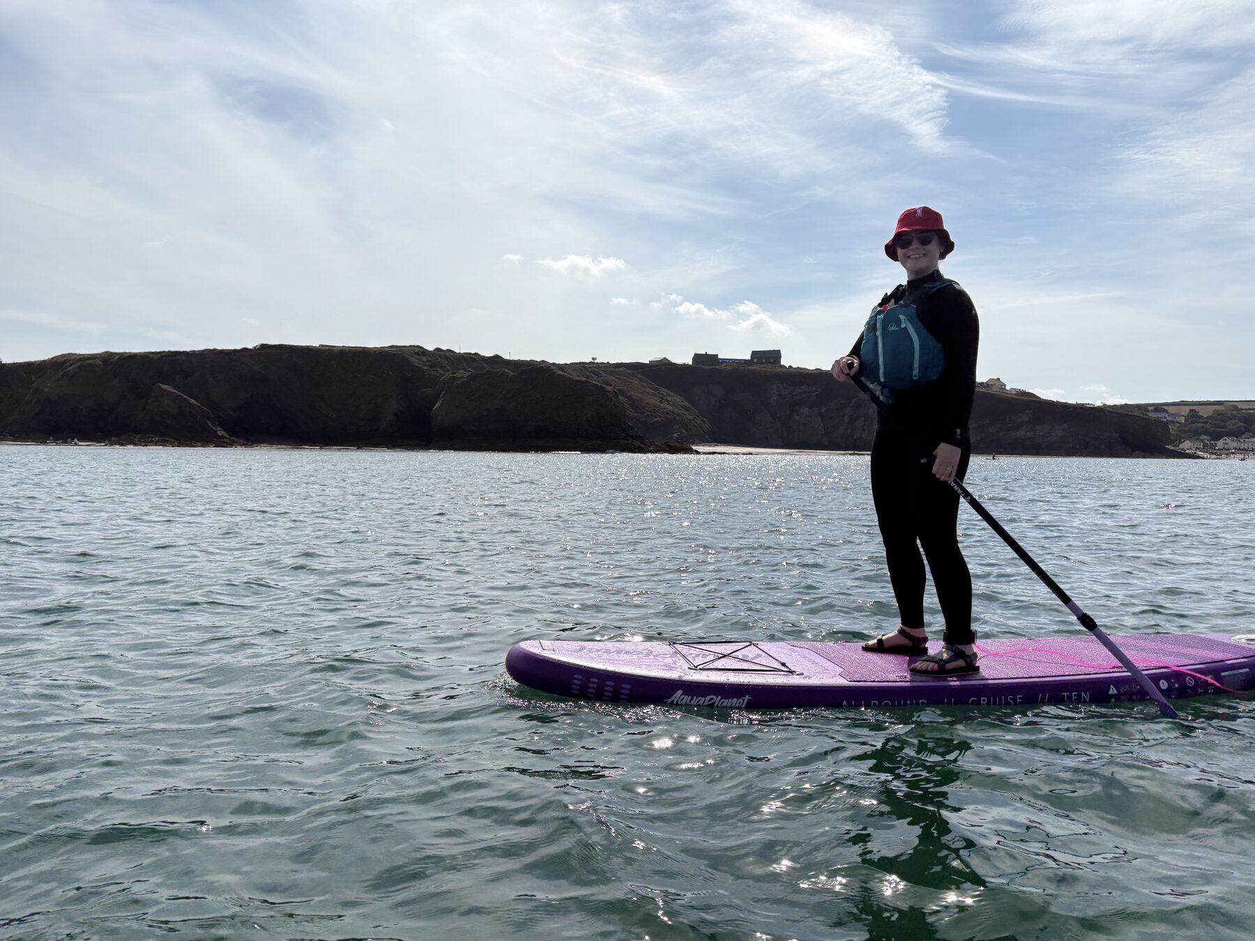 Stand-up paddleboarder wearing a buoyancy aid on open coastal water